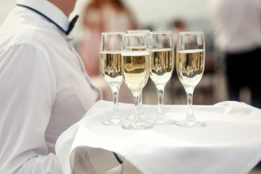 Home | Verhuur van feestmateriaal 3 waiter white carries tray with champagne flutes scaled e1627585473355